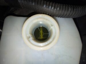 Brake fluid reservoir cap with visible fluid levels during vehicle inspection.