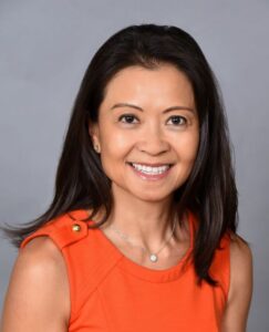 Victoria Repice, Senior Vice President of Product Management at Solera, smiling in a professional headshot wearing an orange sleeveless top against a gray background.