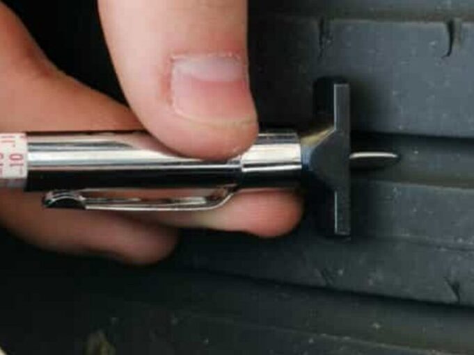 Close-up of a tread depth gauge measuring tire tread wear to check safety and replacement needs.