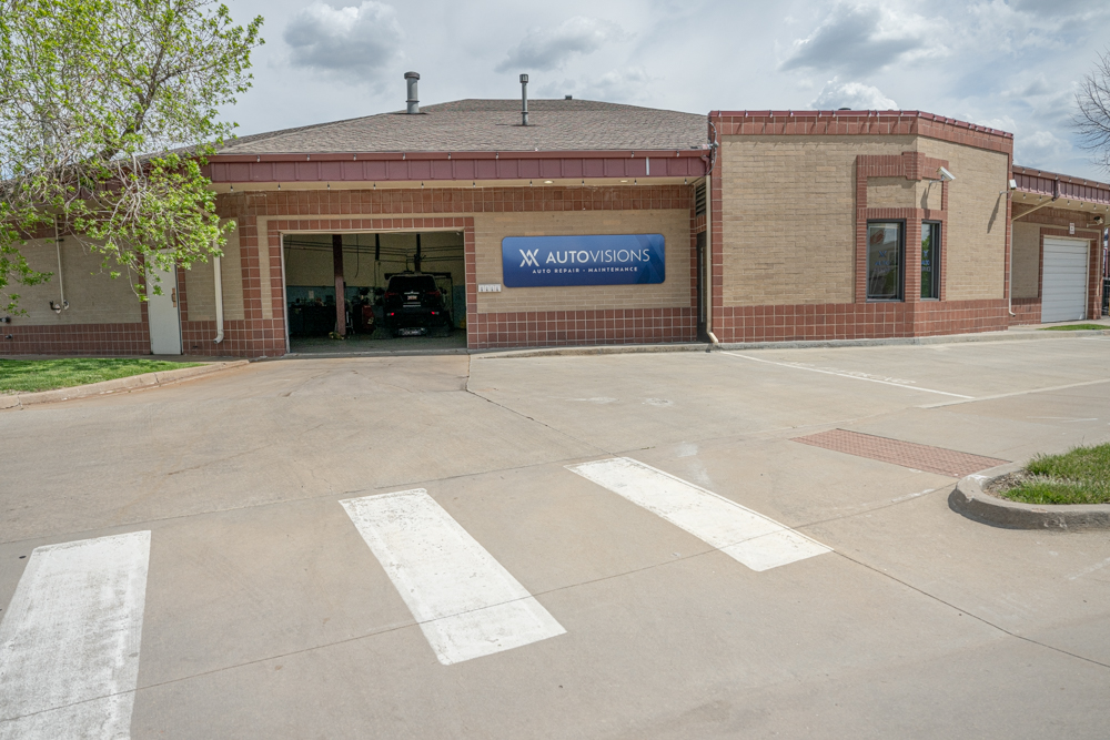 Exterior view of Autovisions, an auto repair and maintenance shop in Englewood, Colorado, showing the entrance bay and building signage on a clear day.