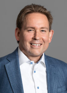 Professional headshot of Konstantin Shirokinskiy, Detroit-based partner at Roland Berger, wearing a blue suit jacket and white shirt.